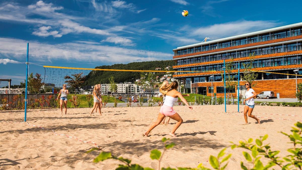 Jenter spiller sandvolleyball i Saunesparken midt i sentrum.
