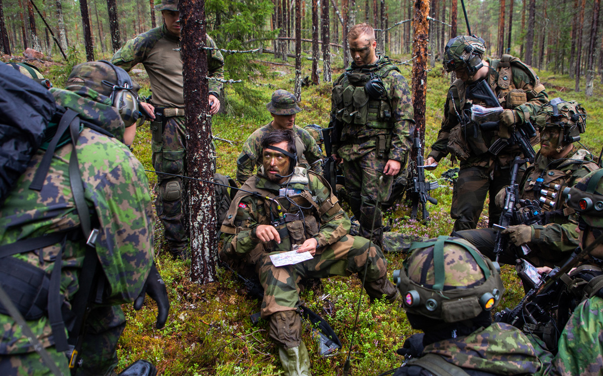 Figur 12.13 Nordiske styrker øver sammen. En troppssjef fra Porsanger bataljon i Finnmark landforsvar gir ordre til norske og finske soldater på øvelse i Nord-Finland i juli 2022.