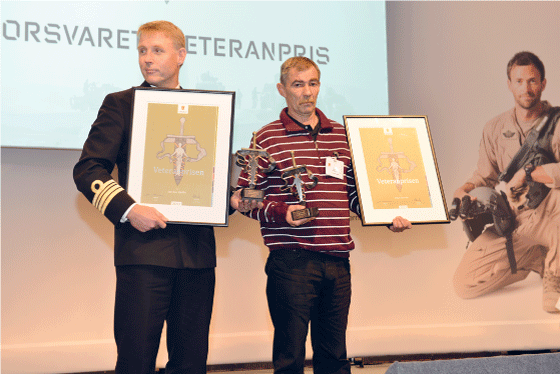 Figur 6.7 Forsvarets veteranpris ble første gang delt ut under Nasjonal veterankonferanse i Bergen i 2013. H.K.H. Kronprins Haakon overrakte prisen til daværende kommandørkaptein Jon Ivar Kjellin (t.v.) og T erje Sæterbø.
