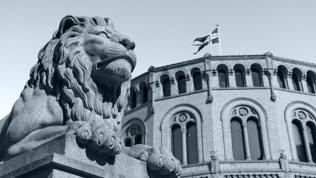 Løvestatue med stortingsbygningen i bakgrunnen
