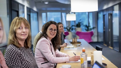 Foto: Justis- og beredskapsdepartementet Kvinnelige ansatte ved siden av hverandre langs et bord.