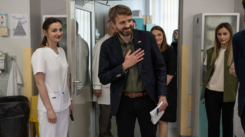 Jan Christian Vestre holder en flat hånd på brystet inne på hjertesykehuset i Kyiv. En hvitkledd ukrainsk helsearbeider står ved siden av ham, samt annet helsepersonell.