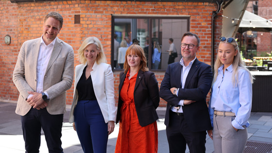 Kvinner og menn står på rekke utenfor en nedlagt industriområde