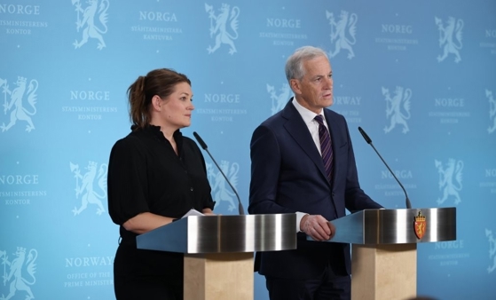 Næringsministeren og statsministeren står bak hver sin talerstol. Blå bakvegg med riksløver.