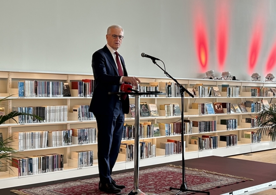 Statsministeren står på en scene foran en rad med bokhyller på biblioteket i Bodø.