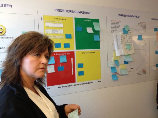 Sykepleier og tavlefører Eva Engen i hjemmetjenesten Los i Lunner står foran tavla hvor de ansatte klistrer postit-lapper med ideer til forbedringer